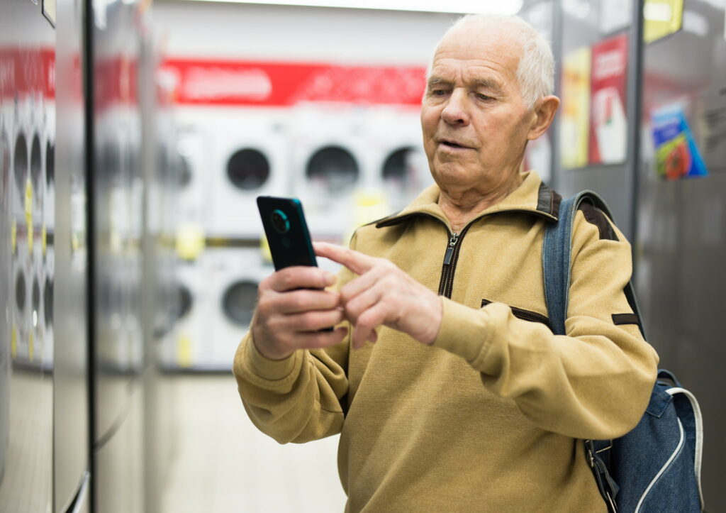 an older man uses a smartphone in a home appliance store